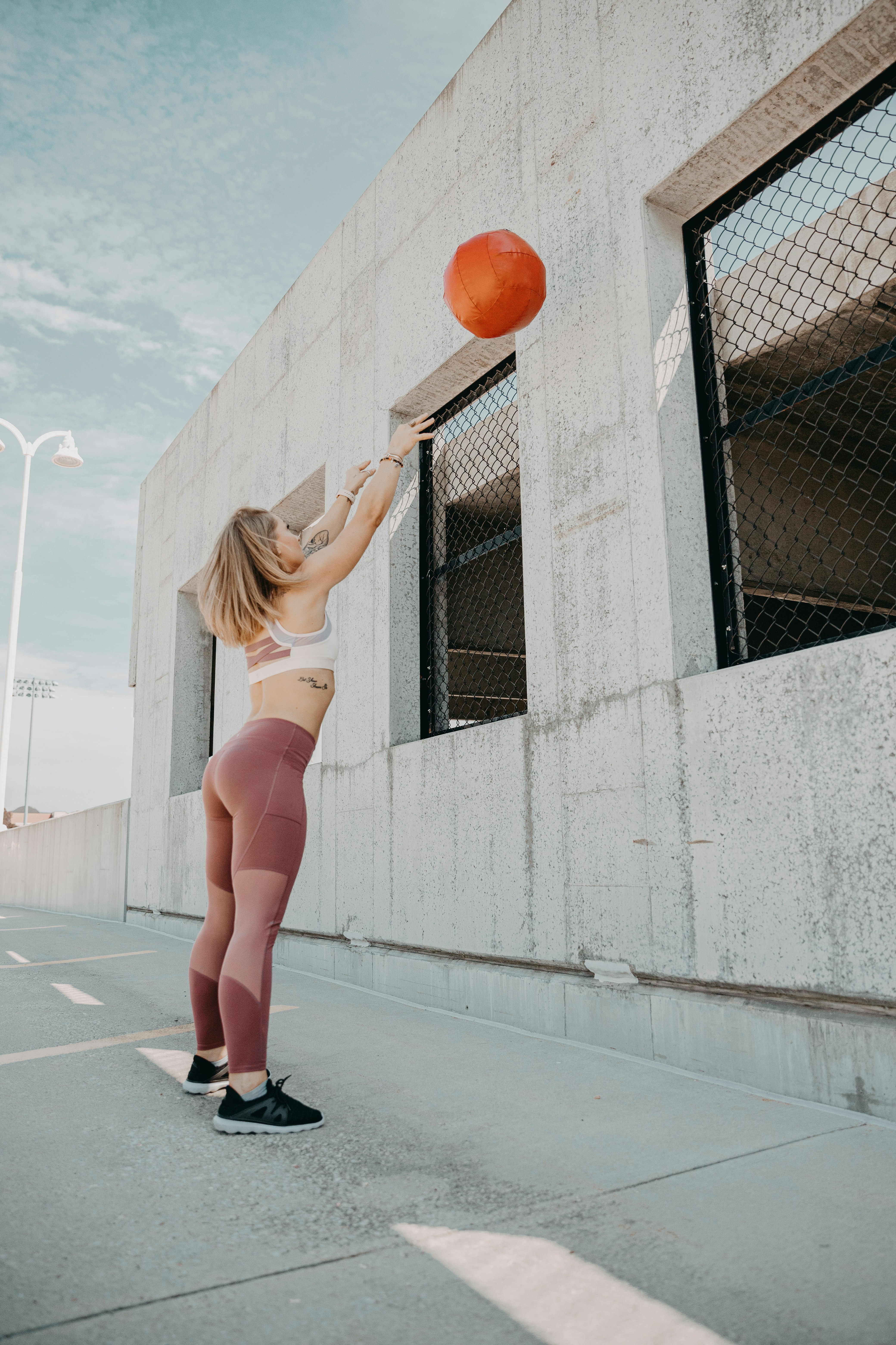 woman in white bikini leaning on chain link fence during daytime